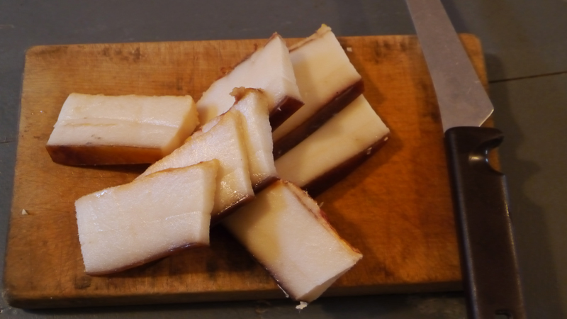 Während der Salat kocht wird Speck in Scheiben geschnitten und in einer Pfanne gebraten.  Wenn er glasig ist, kommt der Speck, ohne das Fett, in die Suppe.